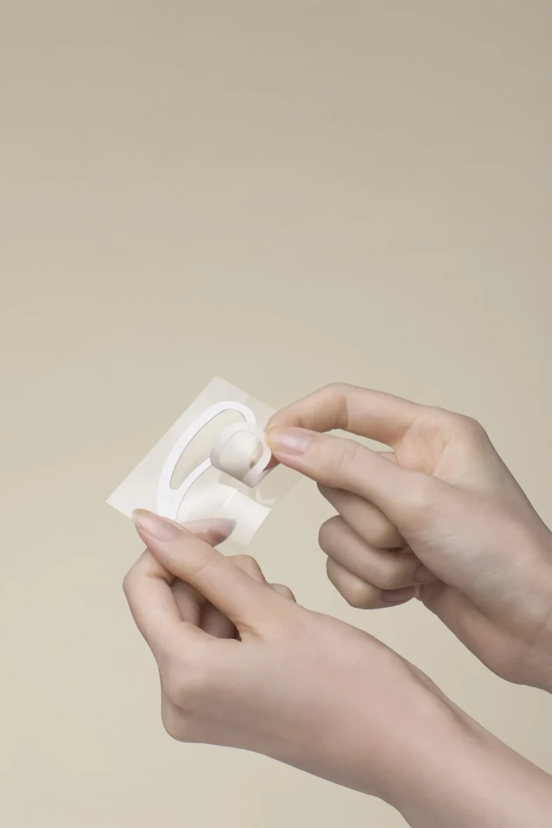 Ruka drži traku za podizanje kapaka iz linije Divote Cosmetics, naglašavajući preciznost korejske kozmetike.