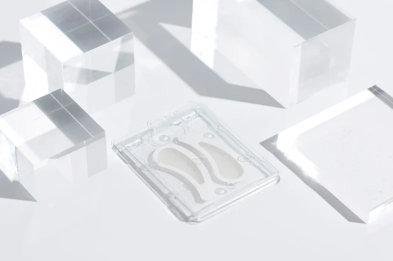 Proizvod Divote Cosmetics inspiriran korejskom kozmetikom, sa jastučićima u providnom pakiranju okruženom prozirnim blokovima u minimalističkom stilu.