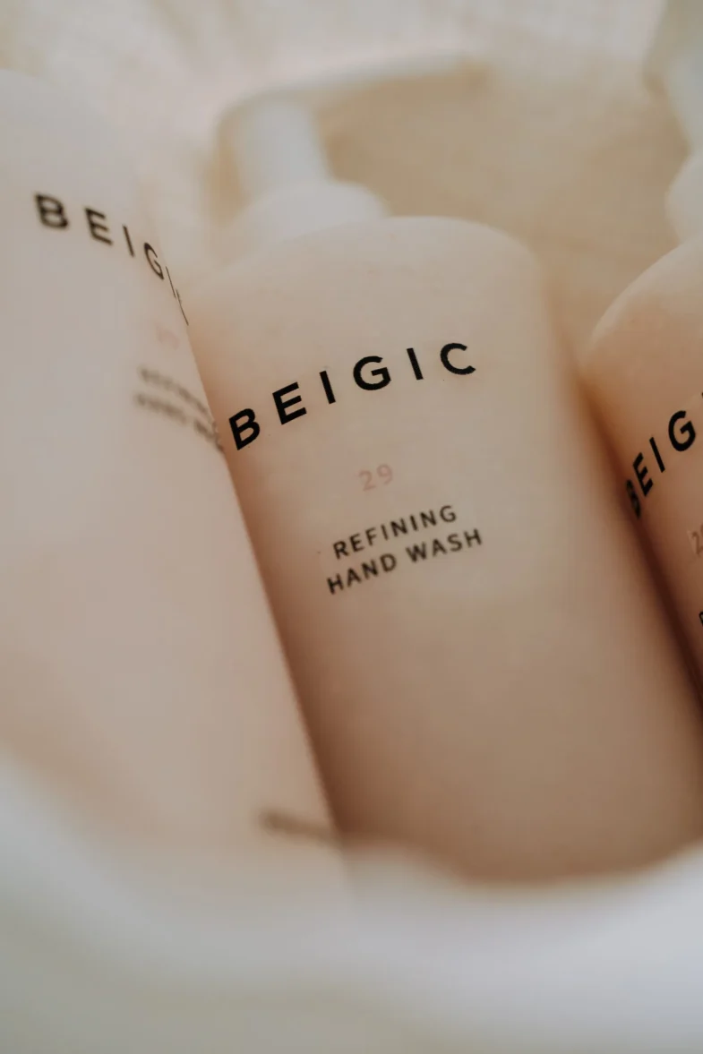 Nekoliko bočica proizvoda marke BEIGIC, označene kao 'Refining Hand Wash', dio divote cosmetics i korejske kozmetike, poredane su u mekom svjetlu s jasnim fokusom na naziv brenda.