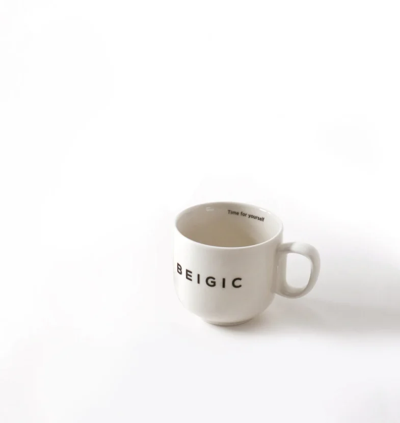 Bijela šalica s natpisom 'BEIGIC', povezana s divote cosmetics i korejskom kozmetikom, na bijeloj pozadini.