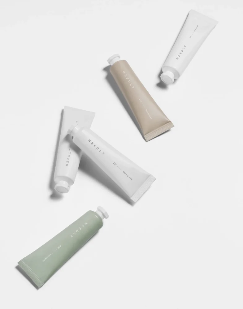 Pet tubica proizvoda korejske kozmetike Needly, koje promovira Divote Cosmetics, raznih boja elegantno raspoređenih na bijeloj pozadini.