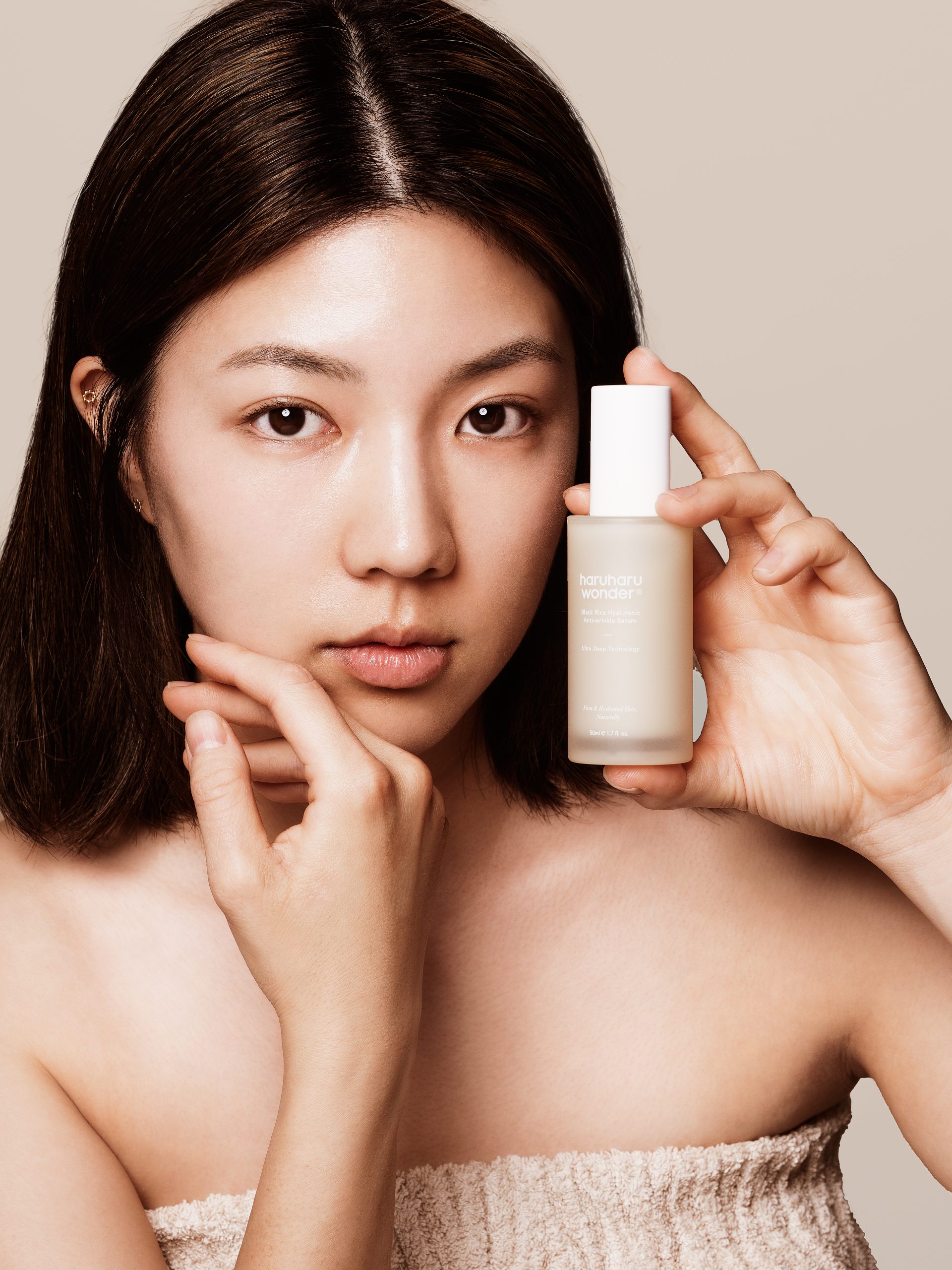 Žena drži bočicu proizvoda "Divote Cosmetics" u ruci, predstavljajući primjer korejske kozmetike, s fokusom na njegu kože.