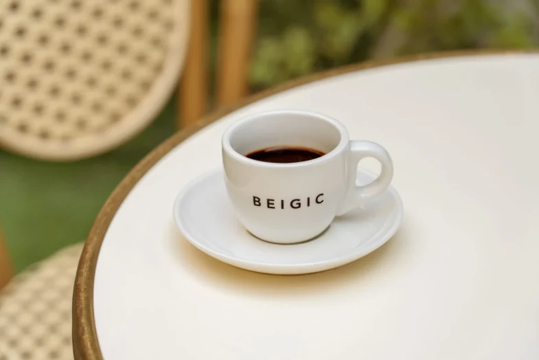 Šalica kave s logotipom 'BEIGIC' na stolu, povezana s konceptom divote cosmetics i korejske kozmetike.