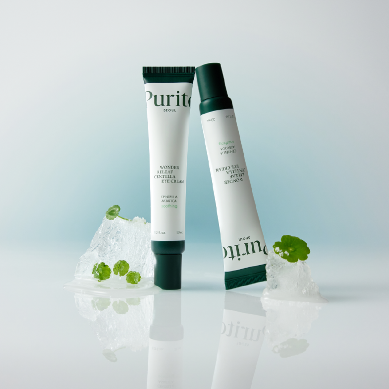 Dva pakiranja kreme za oči "Purito Wonder Relief Centella Eye Cream" postavljena na ledu s biljkama centelle asiatice, koja su dio kolekcije Divote Cosmetics i predstavljaju korejsku kozmetiku.