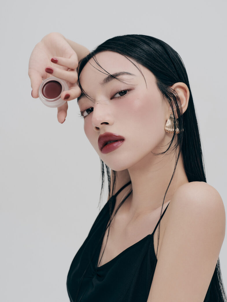 Žena nanosi ruž topli ton koristeći proizvod marke Divote Cosmetics, naglašavajući eleganciju korejske kozmetike.