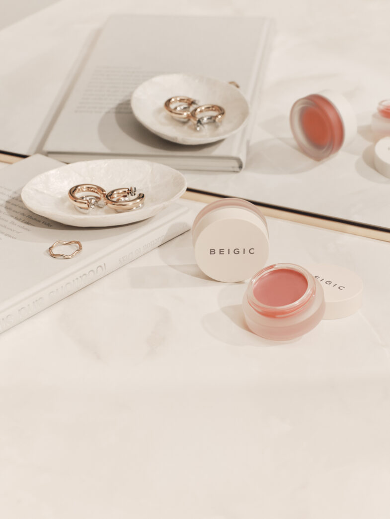 Proizvod korejske kozmetike marke Beigic prikazan na stolu uz nakit, s ključnim riječima 'korejska kozmetika' i 'Divote Cosmetics'.